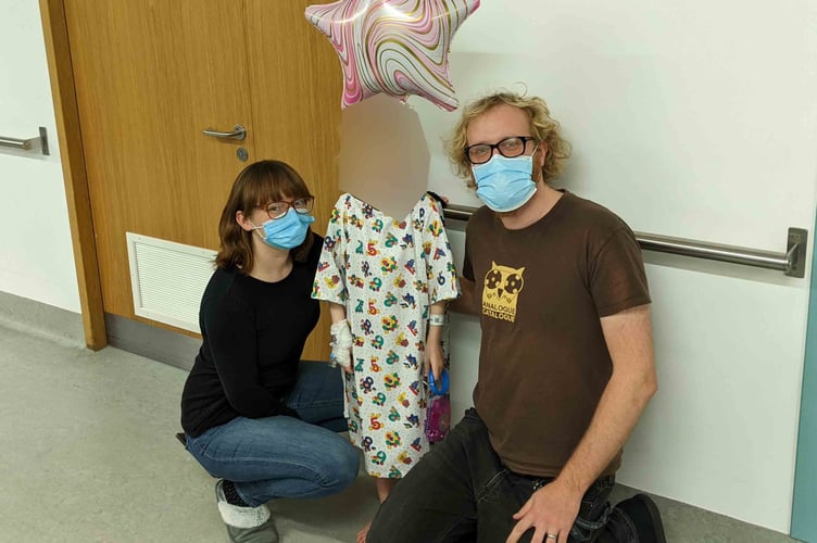 Pic of Evie with her face blurred out as instructed by parents. Evie in hospital gown pictured with mum and dad