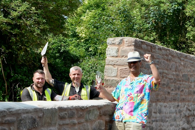 Cllr Paul Symonds celebrating next to a newly renovated stone wall