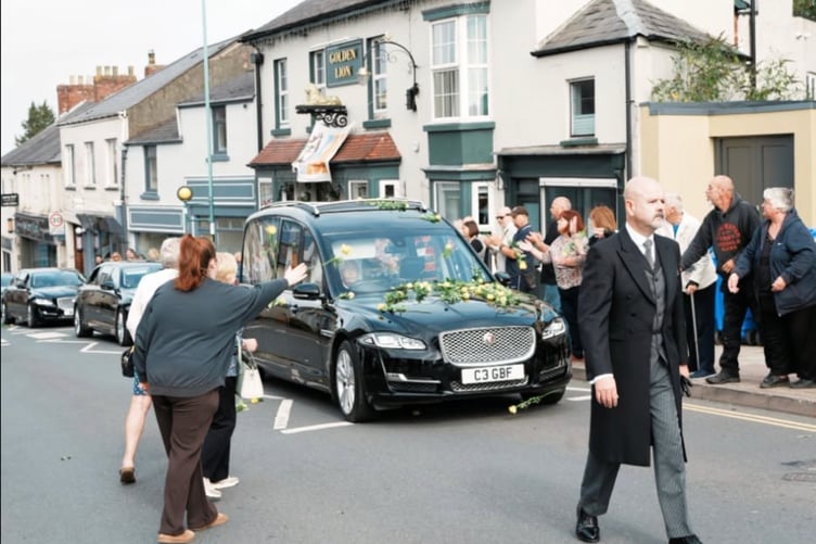 People throw yellow roses as the cortege passes the Golden Lion in High Street. Picture: Tim Holder, Cinderford Town Council.